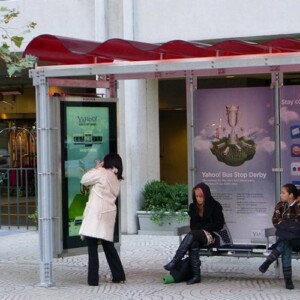 Woman interacting with bus shelter digital display