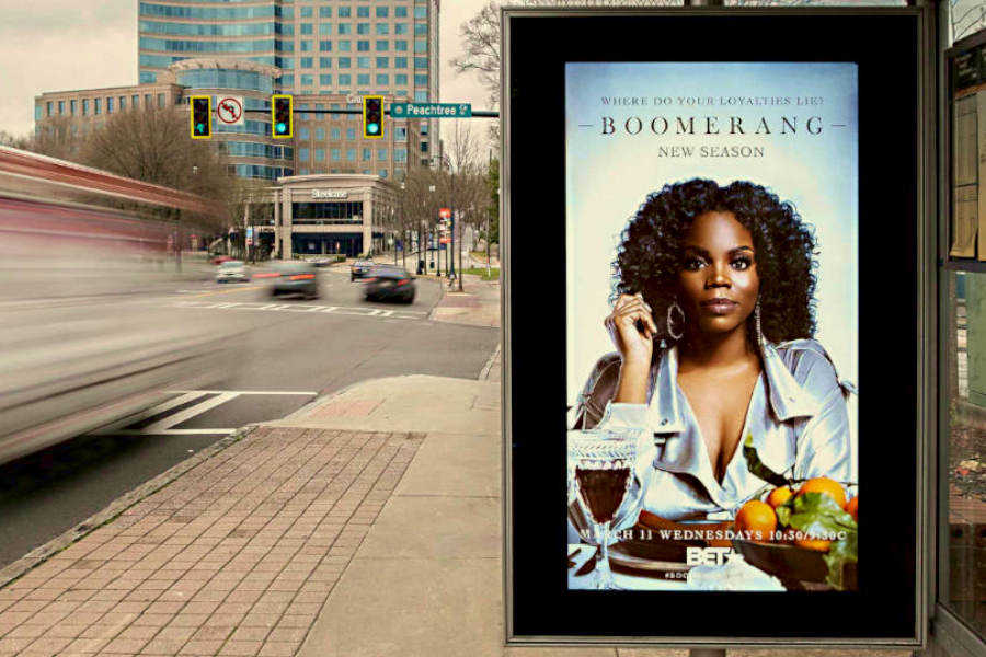 A woman and food in a large digital display at bus station in a city
