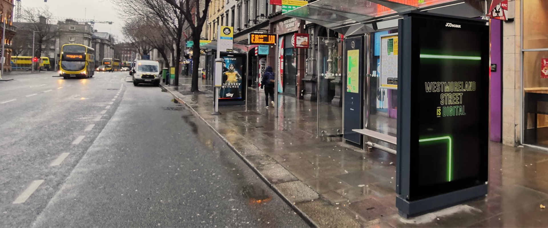 Two bus shelters with digital displays on a city street