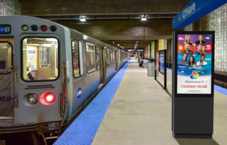 A subway station with a train and a digital display