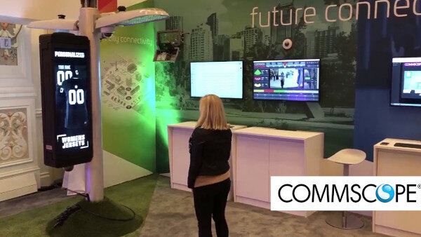 Expo booth scene with a tall digital sign and the Commscope logo