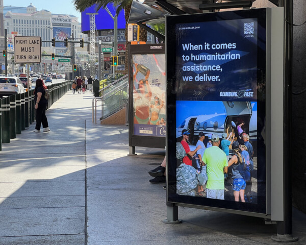 A side walk along a buy street in Las Vegas with large digital displays on the right hand side of the pavement
