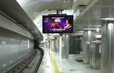 An empty underground, subway station with a digital display with a colorful advertisement