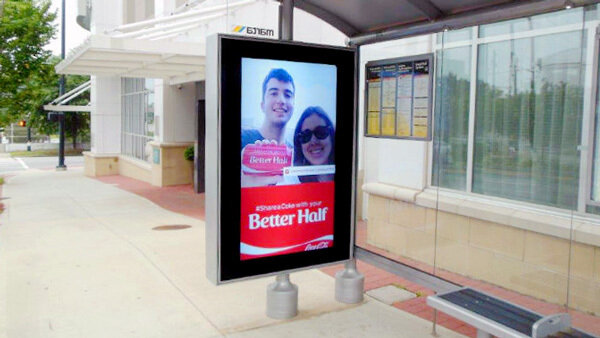 Bus stop advertising kiosk with a red "Better Half" ad on a sidewalk