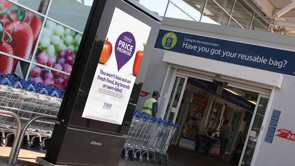Outdoor retail entrance with a digital ad kiosk and shopping carts