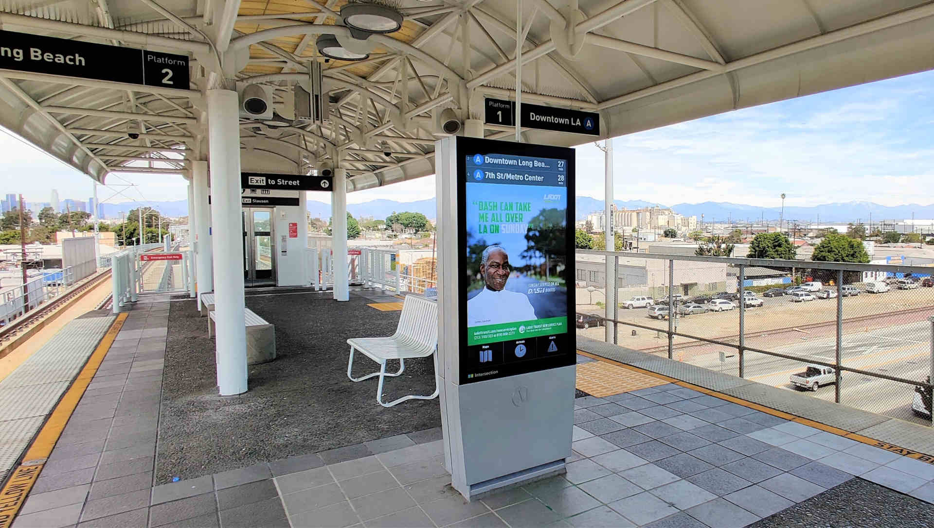 An elevated train station in a covered area over a highway with a digital display