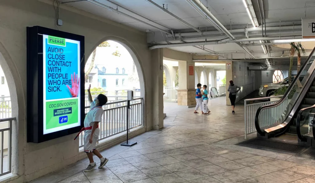 Guests in a covered parking garage - one is interacting with a bright colorful digital display