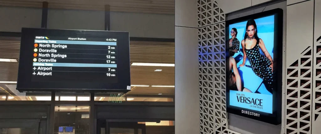 Two digital displays in a subway transit station - one on a wall and one from the ceiling