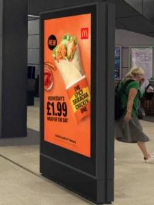 A digital display inside a subway station with a bright and colorful add