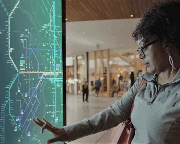 A woman interacting with a subway map on a digital display within a mall space
